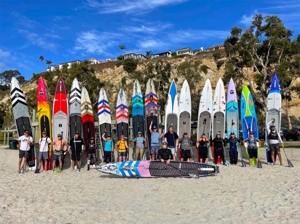 candice appleby with paddleboard in front of sup training club participants standing with paddleboards